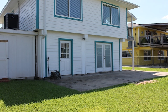 rear view of property featuring a balcony, a yard, a patio area, and central AC