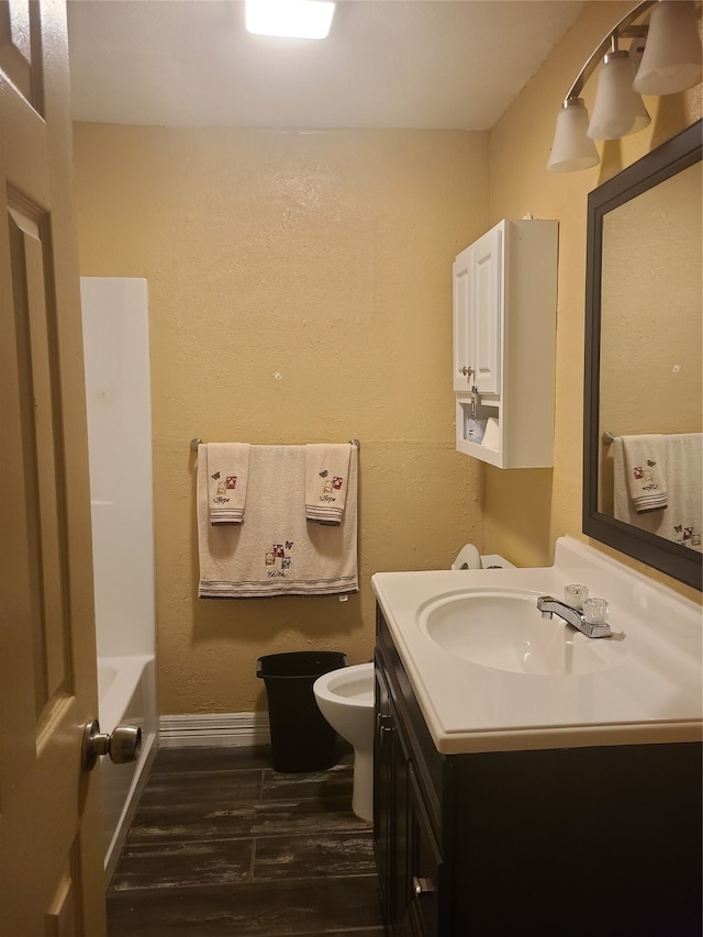 bathroom with vanity, toilet, wood-type flooring, and a washtub