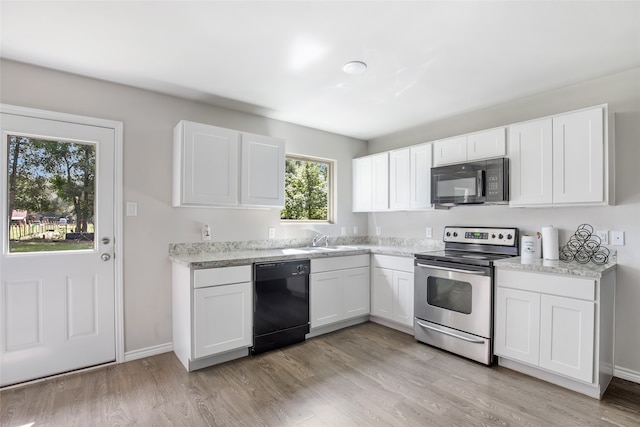 kitchen with light wood-type flooring, white cabinetry, light stone countertops, sink, and black appliances