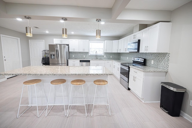 kitchen with white cabinets, tasteful backsplash, a kitchen breakfast bar, and stainless steel appliances