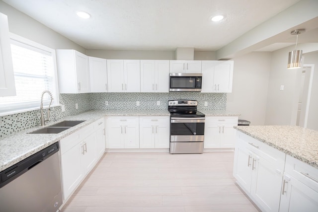 kitchen with sink, decorative backsplash, light stone counters, stainless steel appliances, and white cabinets