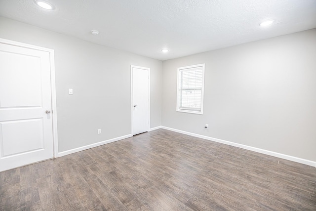 unfurnished room with a textured ceiling and dark wood-type flooring