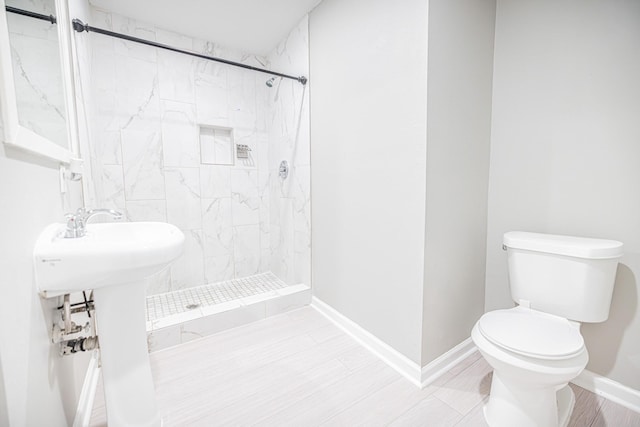 bathroom with toilet, a tile shower, and tile patterned floors