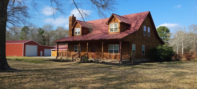 view of front of property featuring a garage, a front yard, an outbuilding, and covered porch