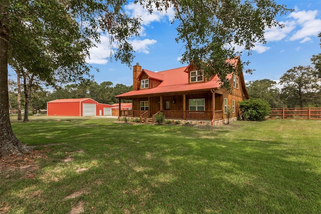 rear view of house featuring a garage, an outbuilding, covered porch, and a lawn