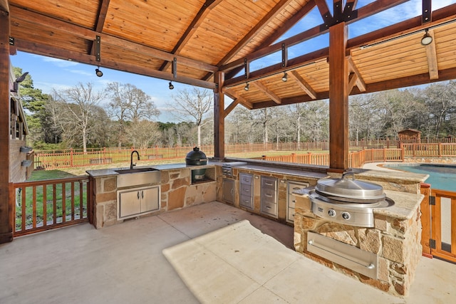 view of patio / terrace featuring sink, grilling area, a fenced in pool, and exterior kitchen