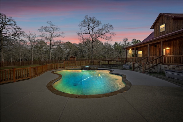 pool at dusk featuring a fireplace and a patio area