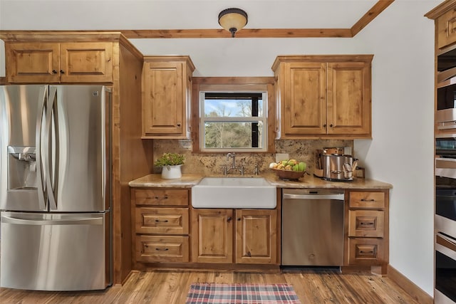 kitchen featuring sink, hardwood / wood-style flooring, stainless steel appliances, and backsplash