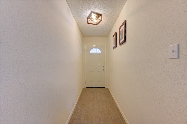 doorway to outside featuring light wood-type flooring and a textured ceiling