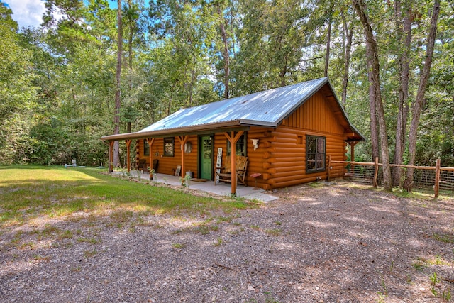 log-style house with a front lawn, fence, metal roof, and log exterior