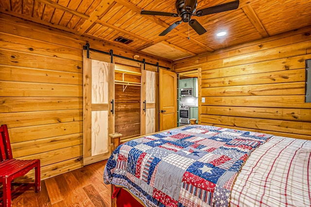 bedroom featuring a barn door, visible vents, wooden ceiling, wood finished floors, and wood walls