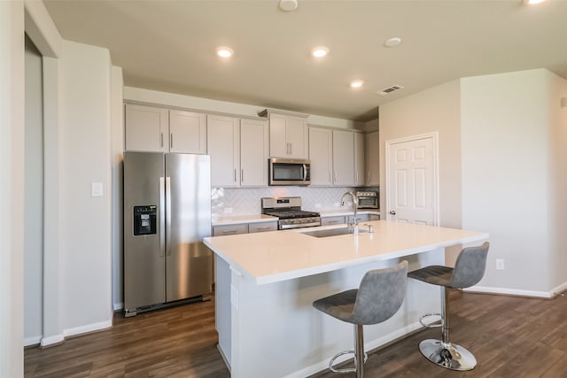 kitchen with sink, a center island with sink, appliances with stainless steel finishes, and dark hardwood / wood-style floors