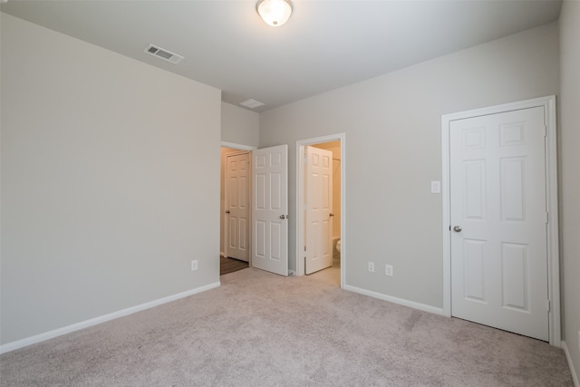 unfurnished bedroom with ensuite bath and light carpet