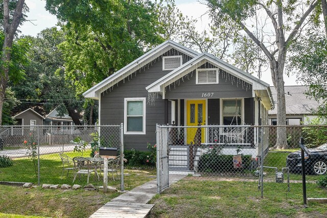 bungalow-style home featuring covered porch and a front lawn