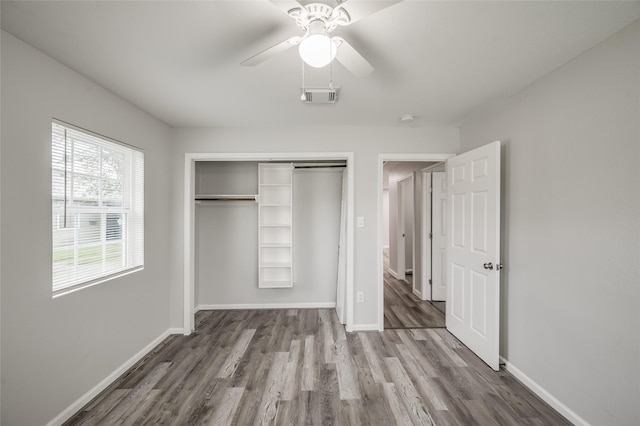 unfurnished bedroom featuring a closet, visible vents, baseboards, and wood finished floors