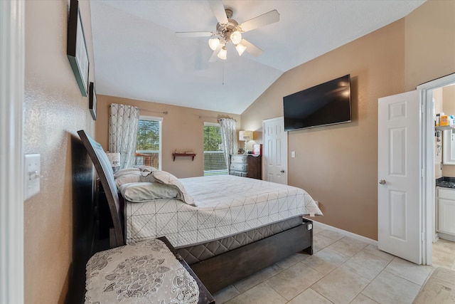 bedroom with ceiling fan, vaulted ceiling, and light tile patterned floors