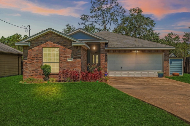 ranch-style house with a garage and a lawn