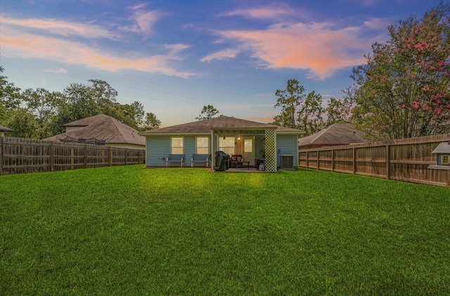 back house at dusk featuring a patio, a lawn, and cooling unit