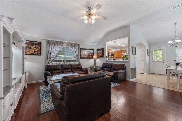 living room with ceiling fan with notable chandelier, dark hardwood / wood-style floors, vaulted ceiling, and plenty of natural light