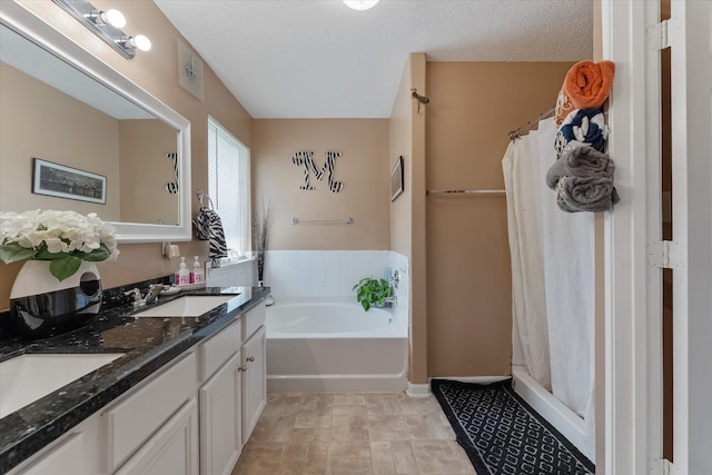 bathroom with a textured ceiling, independent shower and bath, dual bowl vanity, and tile patterned floors