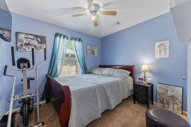 carpeted bedroom featuring ceiling fan and a textured ceiling