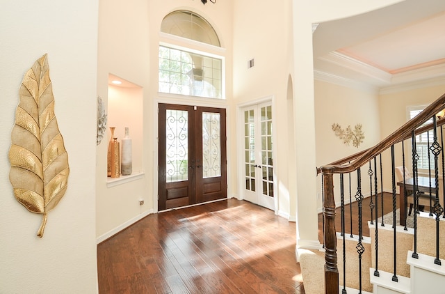 entryway featuring a towering ceiling, french doors, a tray ceiling, and wood-type flooring