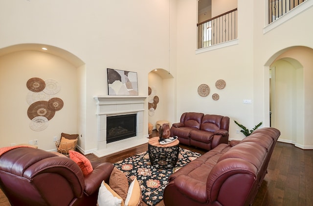 living room with dark wood-type flooring and a towering ceiling