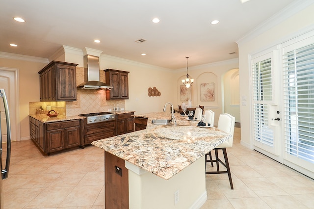 kitchen with wall chimney range hood, decorative backsplash, pendant lighting, stainless steel gas cooktop, and sink