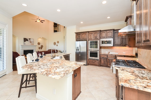 kitchen with ceiling fan, decorative backsplash, a large island, sink, and stainless steel appliances