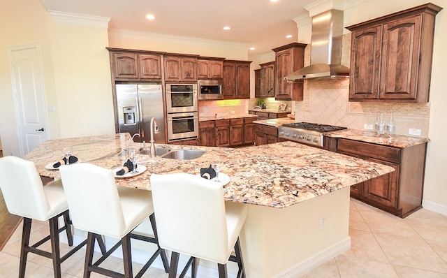 kitchen with a kitchen breakfast bar, backsplash, wall chimney exhaust hood, appliances with stainless steel finishes, and light tile patterned floors