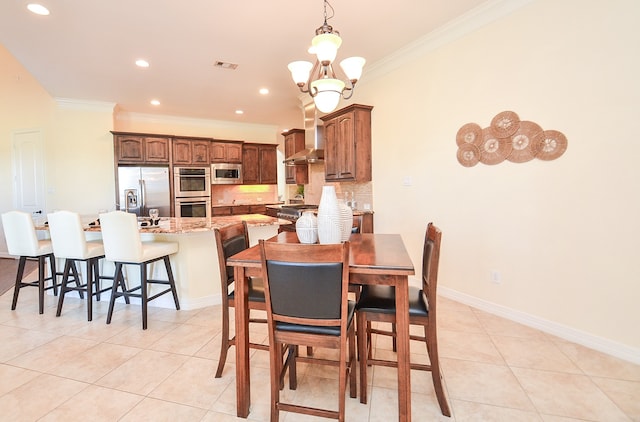 dining area with a notable chandelier, light tile patterned floors, and ornamental molding