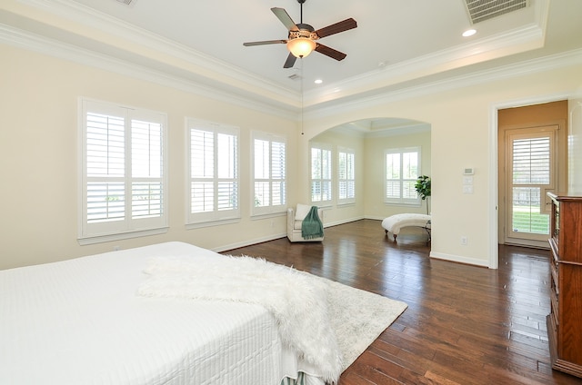 bedroom with ceiling fan, dark wood-type flooring, a raised ceiling, and crown molding