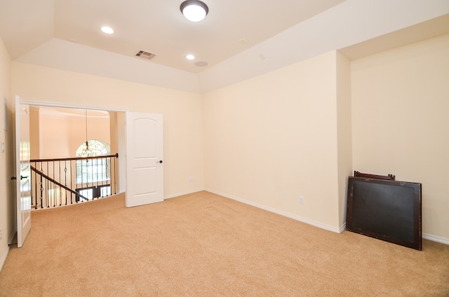 carpeted empty room with a tray ceiling and lofted ceiling