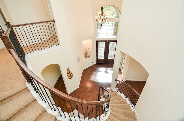 foyer entrance with a high ceiling, french doors, wood-type flooring, and a chandelier