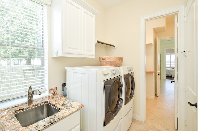 laundry area featuring light tile patterned flooring, sink, washer and clothes dryer, and cabinets