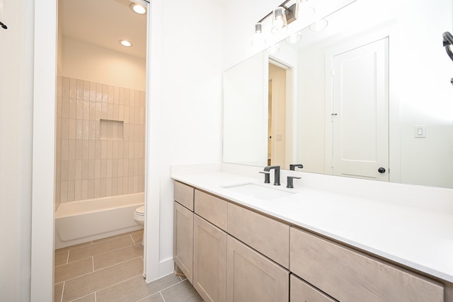 full bathroom with tile patterned flooring, vanity, tiled shower / bath combo, and toilet