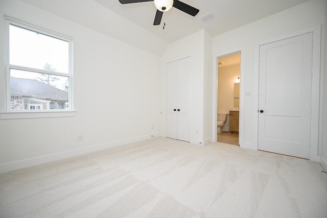 unfurnished bedroom featuring ensuite bath, light carpet, and ceiling fan