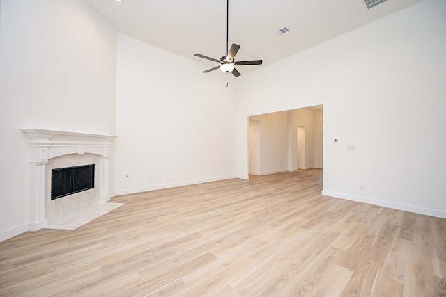 unfurnished living room with ceiling fan, light wood-type flooring, a fireplace, and high vaulted ceiling