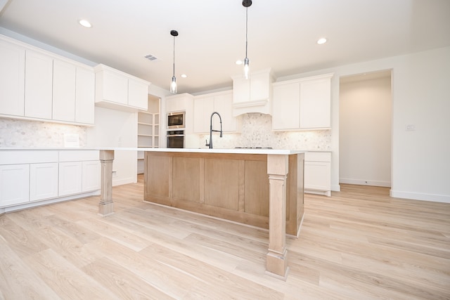 kitchen featuring white cabinetry, a kitchen island with sink, light hardwood / wood-style floors, and appliances with stainless steel finishes