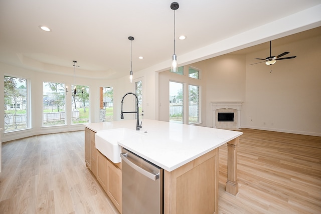 kitchen with light brown cabinets, a center island with sink, sink, light hardwood / wood-style flooring, and stainless steel dishwasher