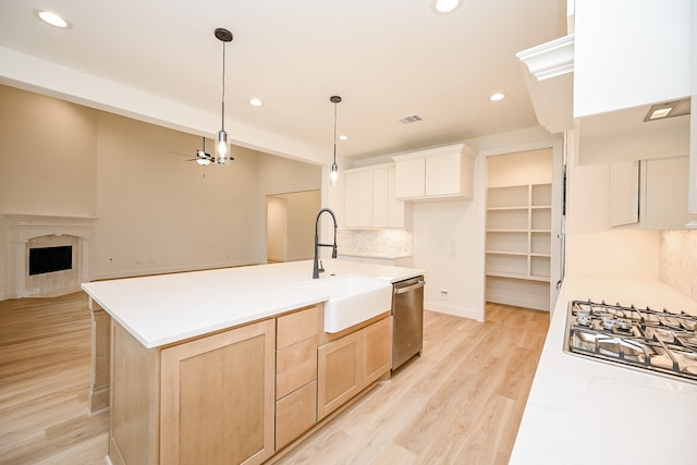 kitchen with ceiling fan, dishwasher, light brown cabinets, sink, and a kitchen island with sink