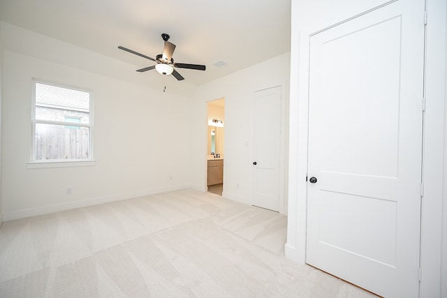 unfurnished bedroom featuring ensuite bath, ceiling fan, a closet, and light carpet