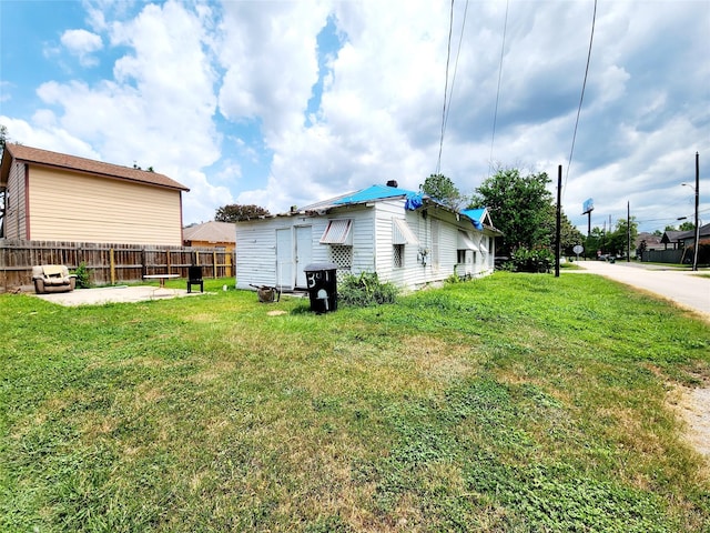 view of side of home featuring a yard, fence, and a patio area