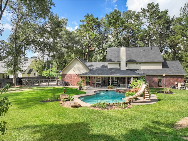 view of swimming pool featuring a yard, a patio area, and a water slide