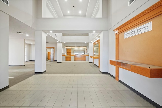 foyer featuring visible vents, light carpet, and a towering ceiling