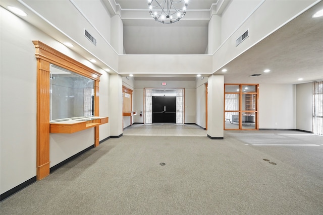 foyer entrance featuring a high ceiling, a notable chandelier, and light colored carpet