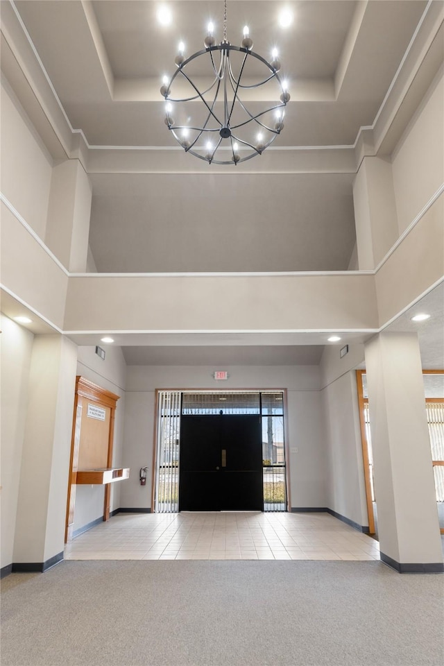 interior space with light carpet, a towering ceiling, and a tray ceiling