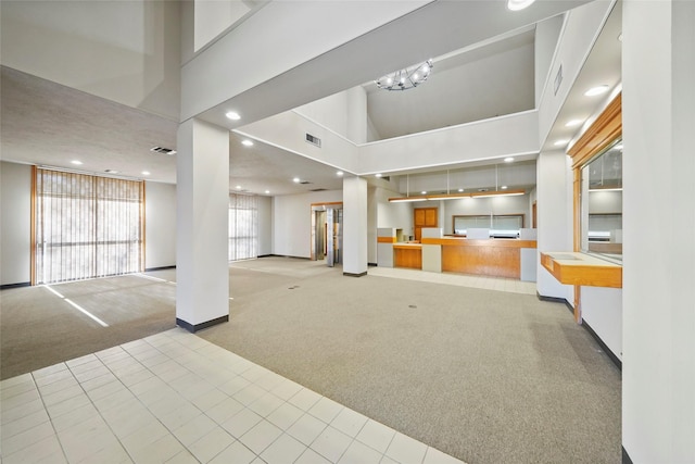 unfurnished living room featuring high vaulted ceiling, recessed lighting, light colored carpet, visible vents, and baseboards