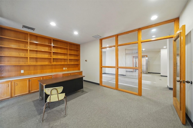 unfurnished office with light carpet, visible vents, built in desk, and recessed lighting