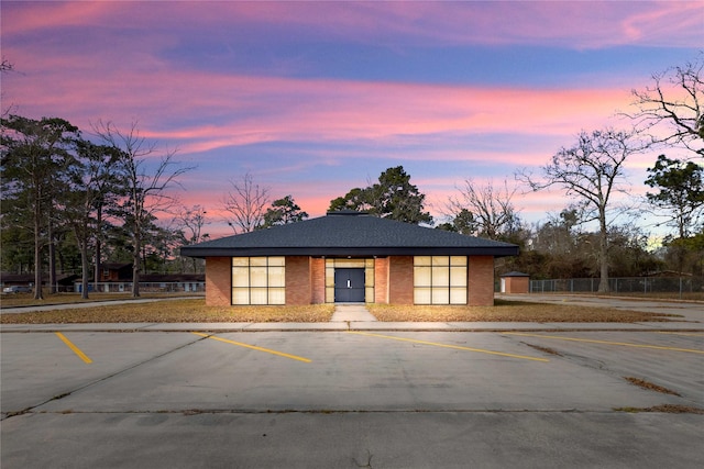 view of front of property featuring uncovered parking, brick siding, and fence